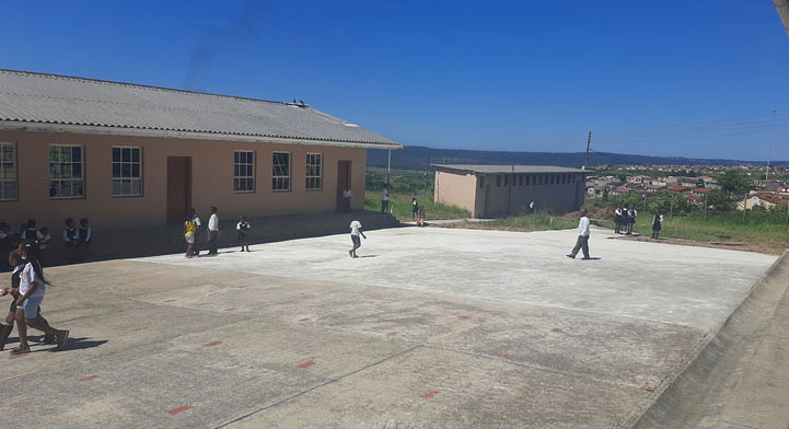 A group of children joyfully playing soccer on a concrete floor, showcasing teamwork and enthusiasm in their game.