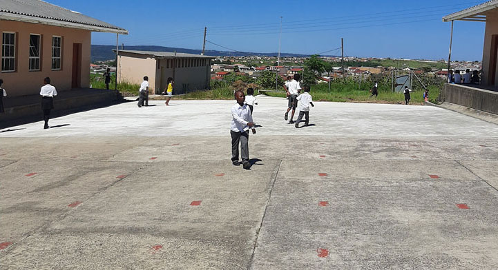 A group of children joyfully playing soccer on a concrete floor, showcasing teamwork and enthusiasm in their game.