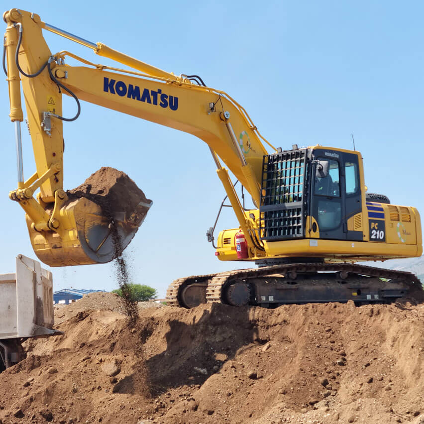 A yellow excavator is actively digging into a large pile of dirt at a construction site, showcasing its powerful machinery.